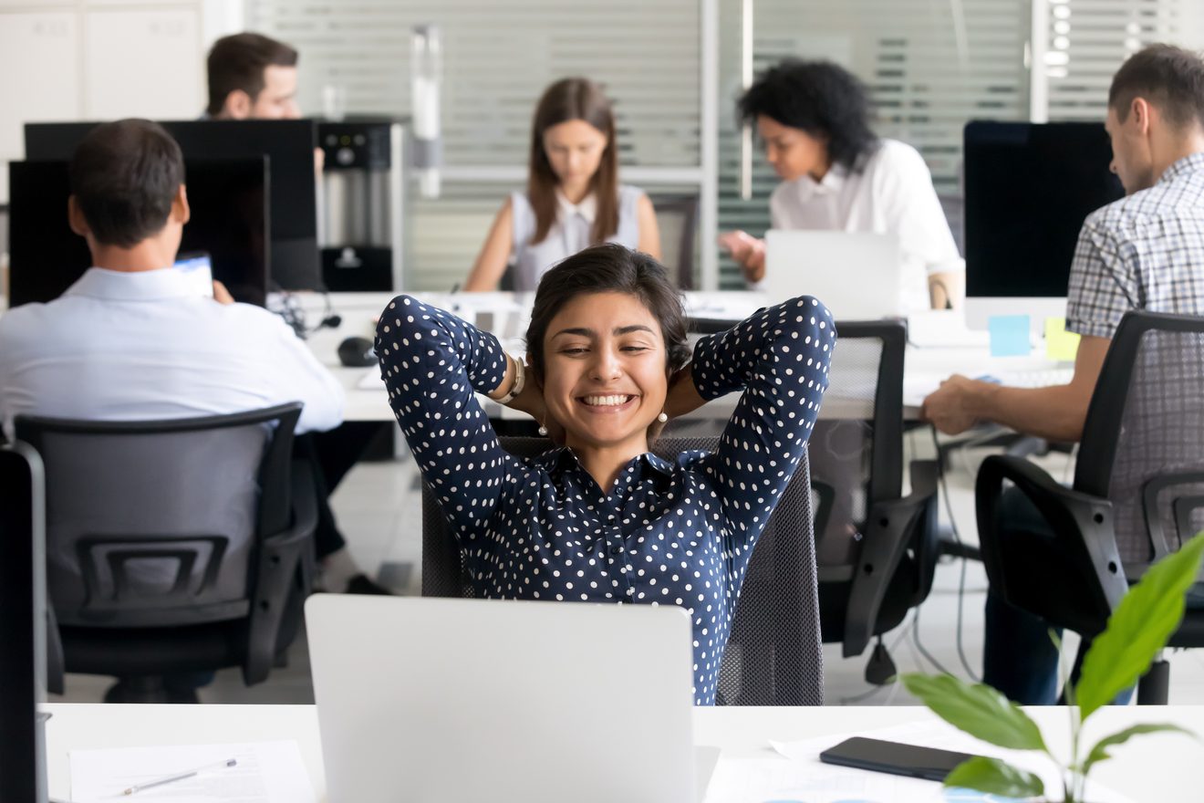 &Eacute;quipe en open space, une collaboratrice d&eacute;tendue devant son poste de travail